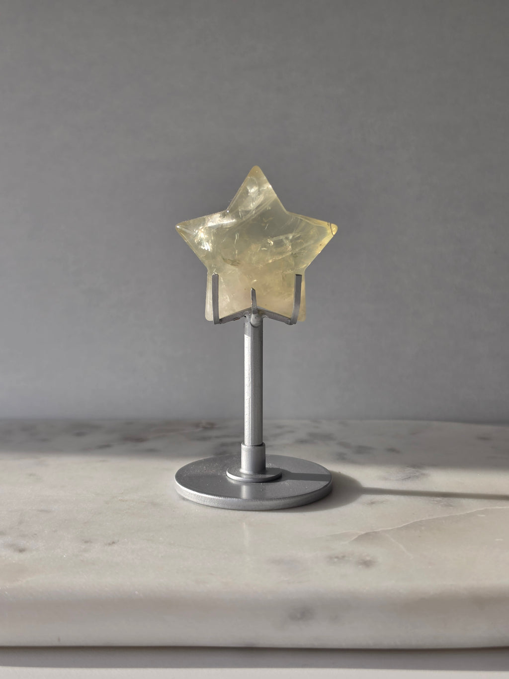 Natural citrine crystal star on a silver stand, featuring translucent golden tones and unique crystal formations, Stone & Bloom statement decor