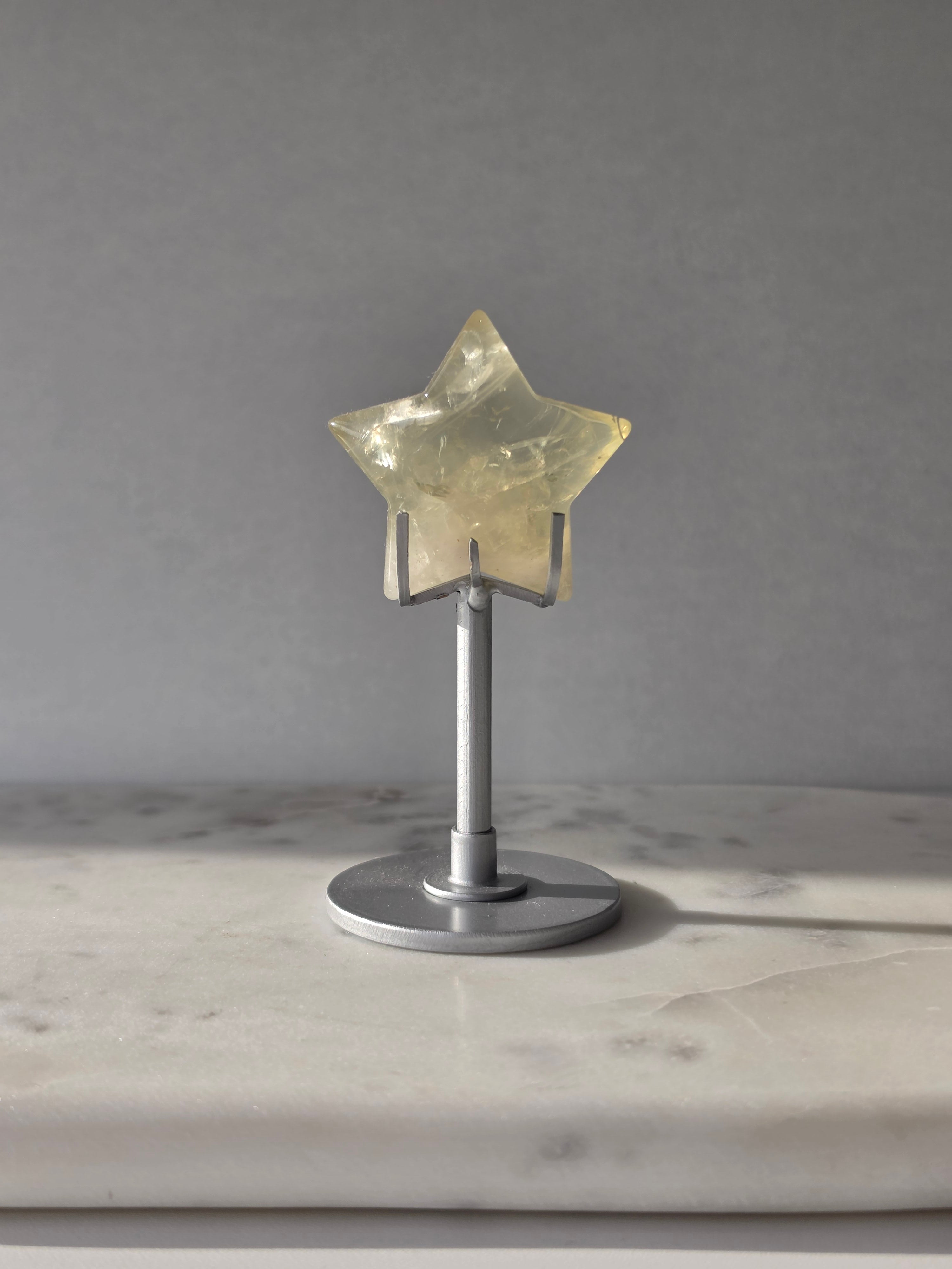 Natural citrine crystal star on a silver stand, featuring translucent golden tones and unique crystal formations, Stone & Bloom statement decor