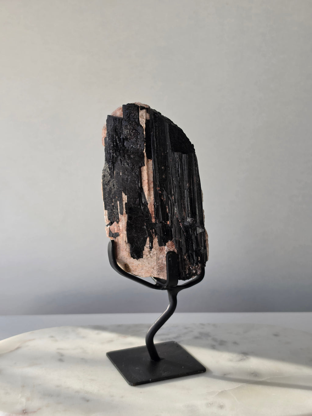 Black Tourmaline on Feldspar matrix from Brazil featuring naturally formed black crystals, contrasting pale matrix, black display stand, 910g, 19.5 × 6.5cm.
