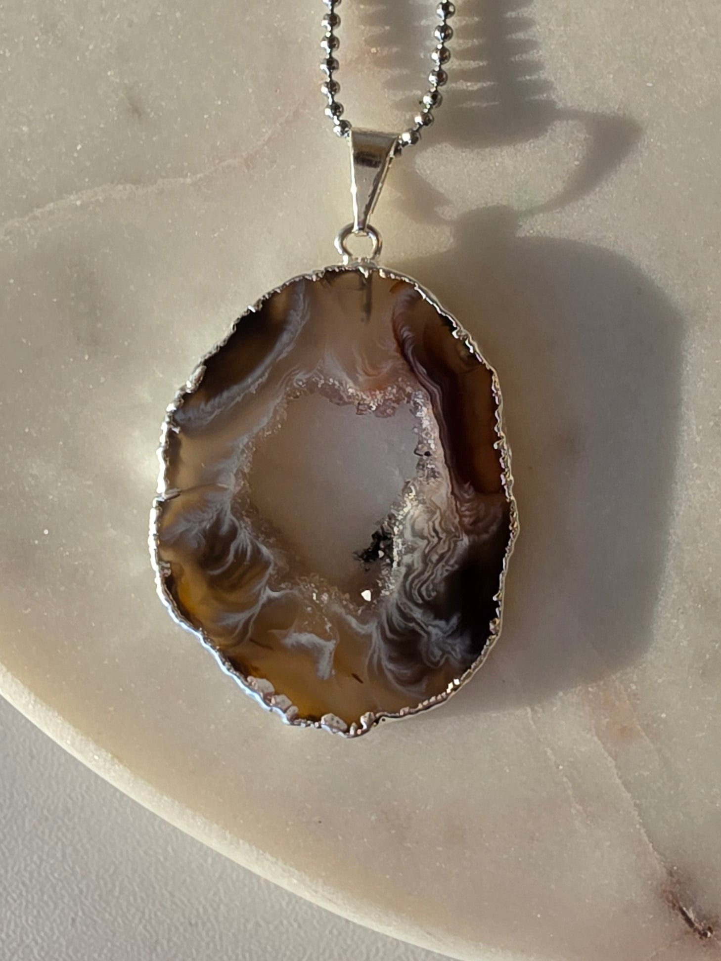 "Brazilian Agate Geode Slice Pendant in natural [brown/black/grey] tones on a silver plated chain with sparkling druzy crystal formations"