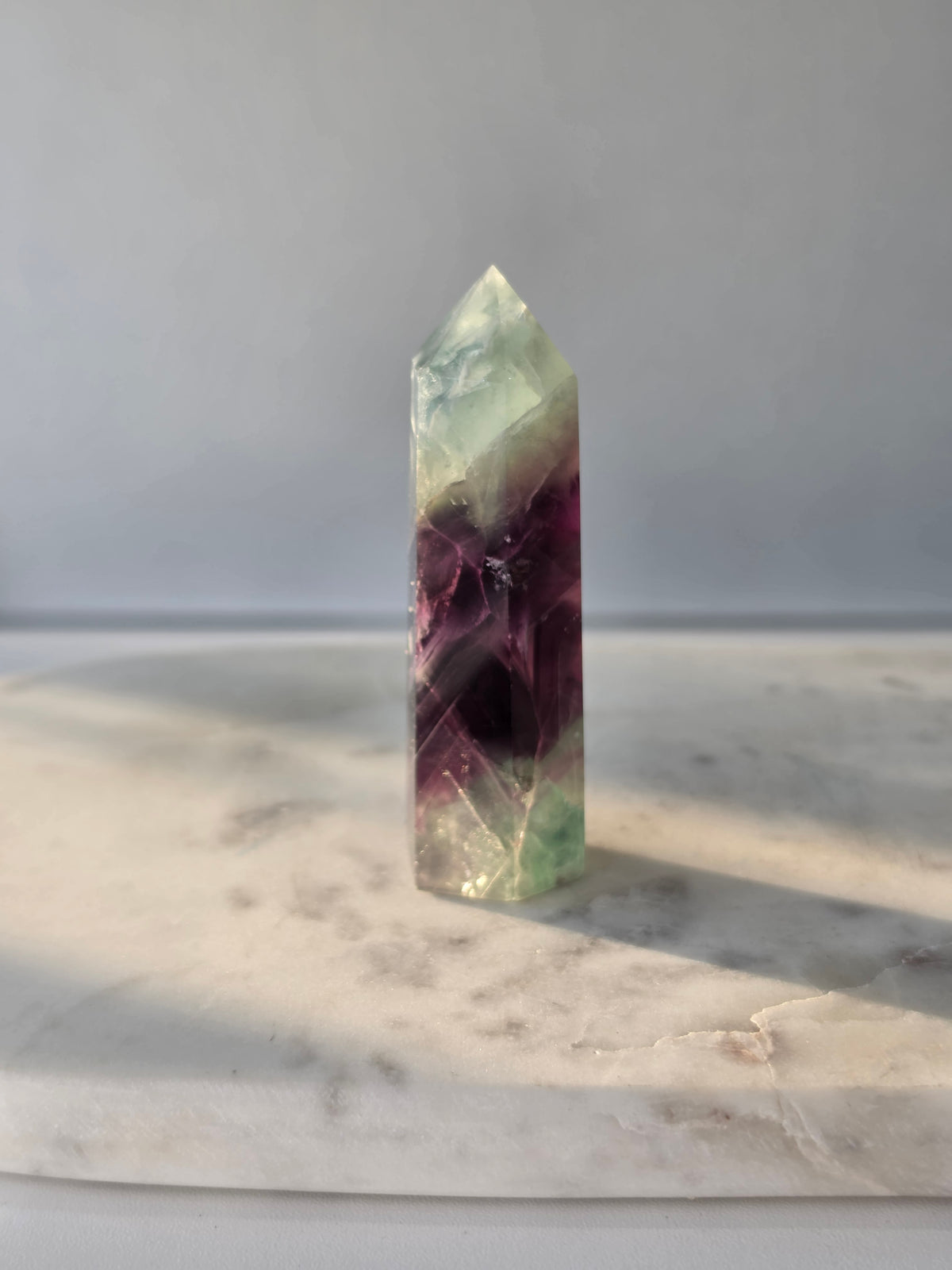 Natural Fluorite crystal point with deep purple and light green colour zoning, transparent polished finish and unique internal formations