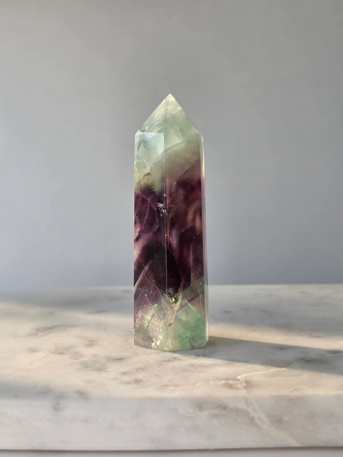 Natural Fluorite crystal point with deep purple and light green colour zoning, transparent polished finish and unique internal formations