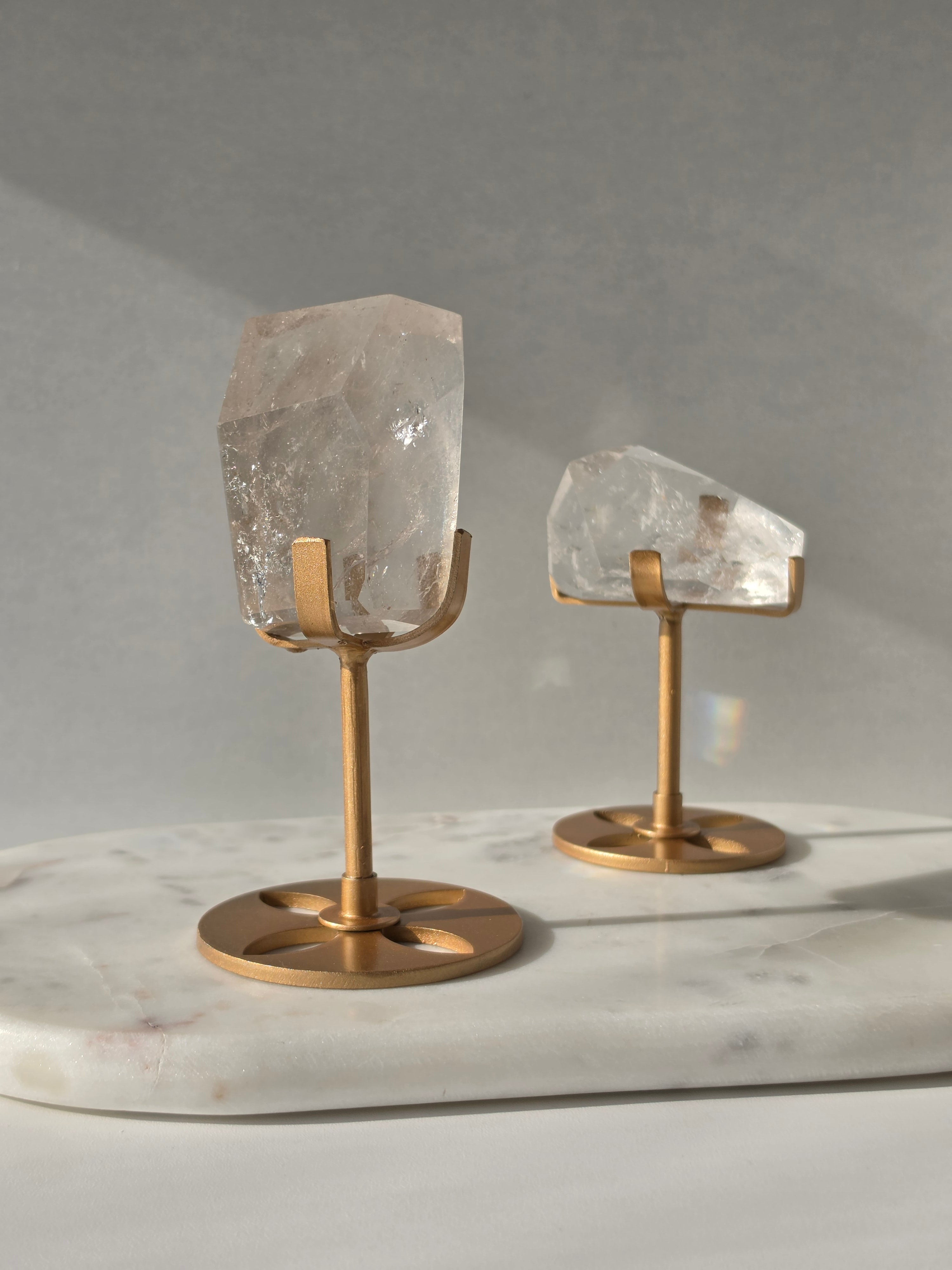 Clear Quartz freeform crystal with natural internal inclusions and luminous clarity, displayed on an elegant gold-finished stand.