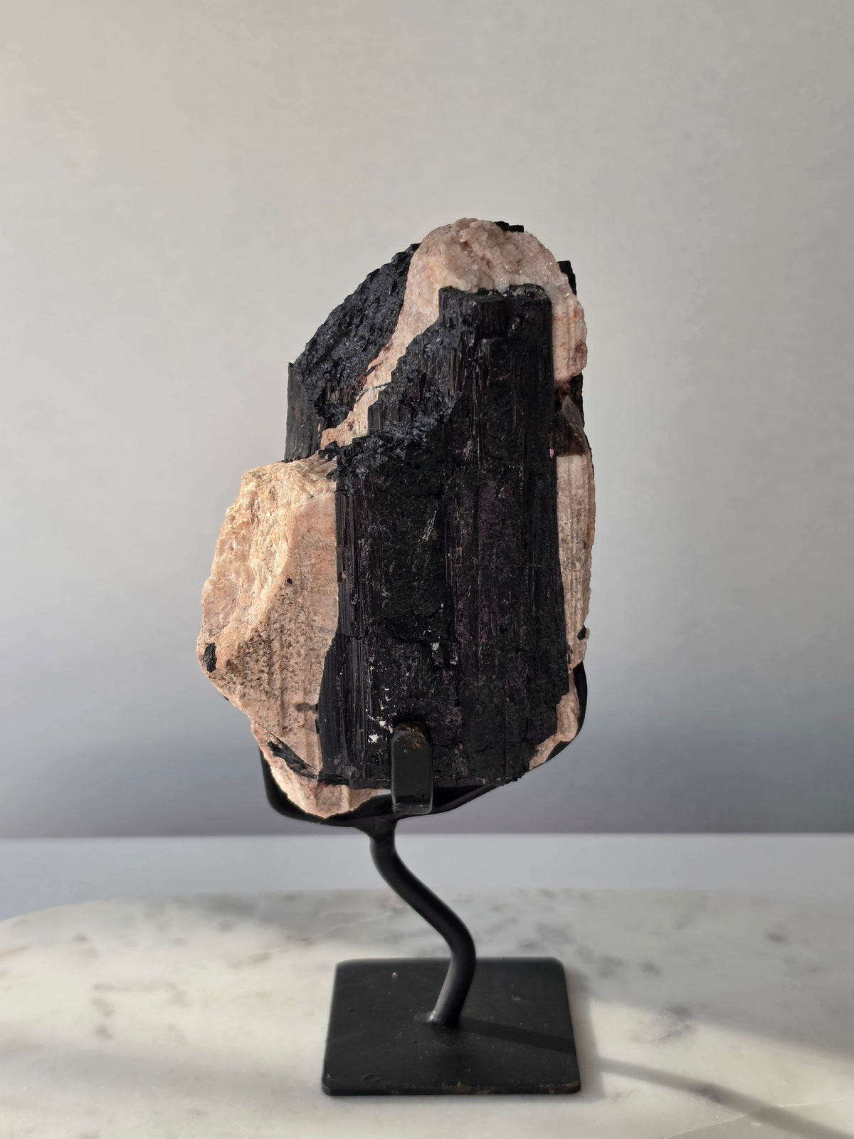 Black Tourmaline on Feldspar matrix from Brazil featuring naturally formed black crystals, contrasting pale matrix, black display stand, 910g, 19.5 × 6.5cm.