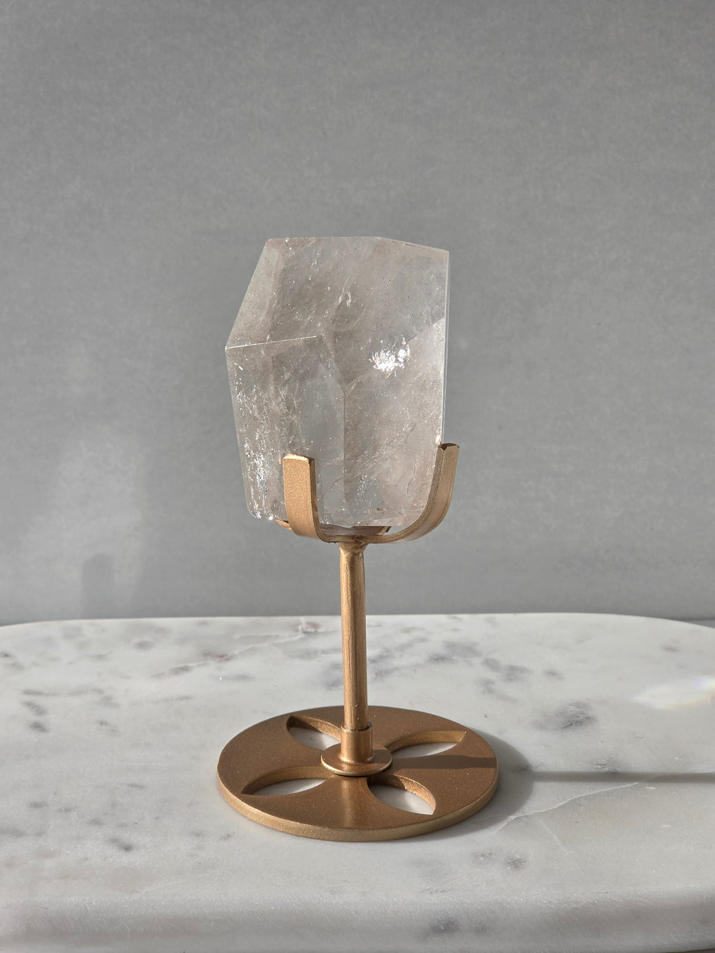 Clear Quartz freeform crystal with subtle smoky-grey translucence, natural internal inclusions and luminous clarity, displayed on an elegant gold-finished stand.