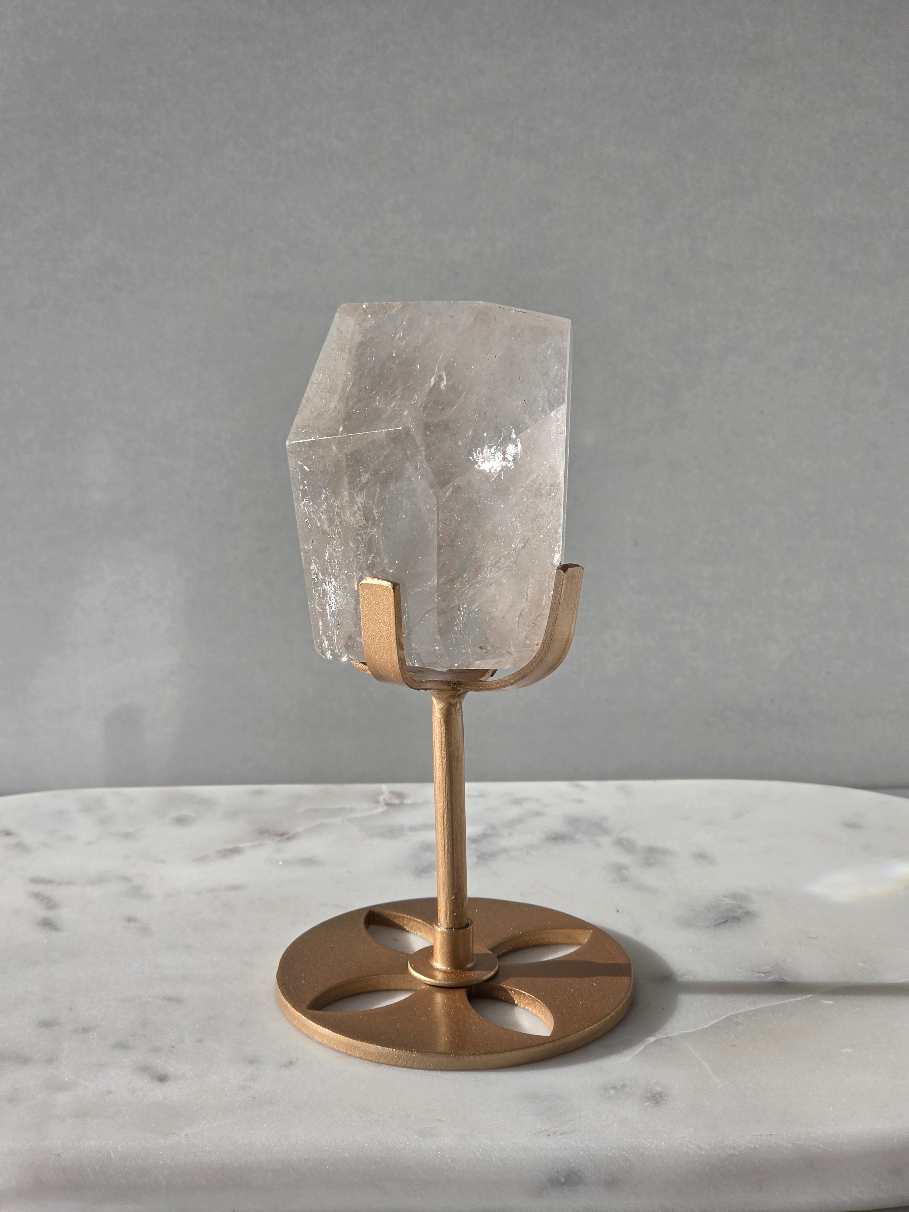 Clear Quartz freeform crystal with subtle smoky-grey translucence, natural internal inclusions and luminous clarity, displayed on an elegant gold-finished stand.