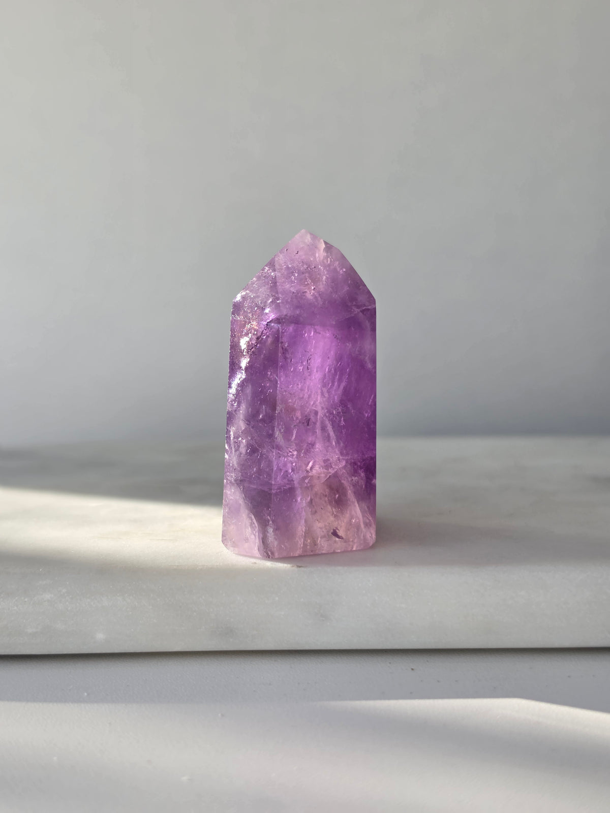 High clarity purple Amethyst tower from Brazil featuring rich violet and lavender hues, translucent crystal formations and polished reflective facets.