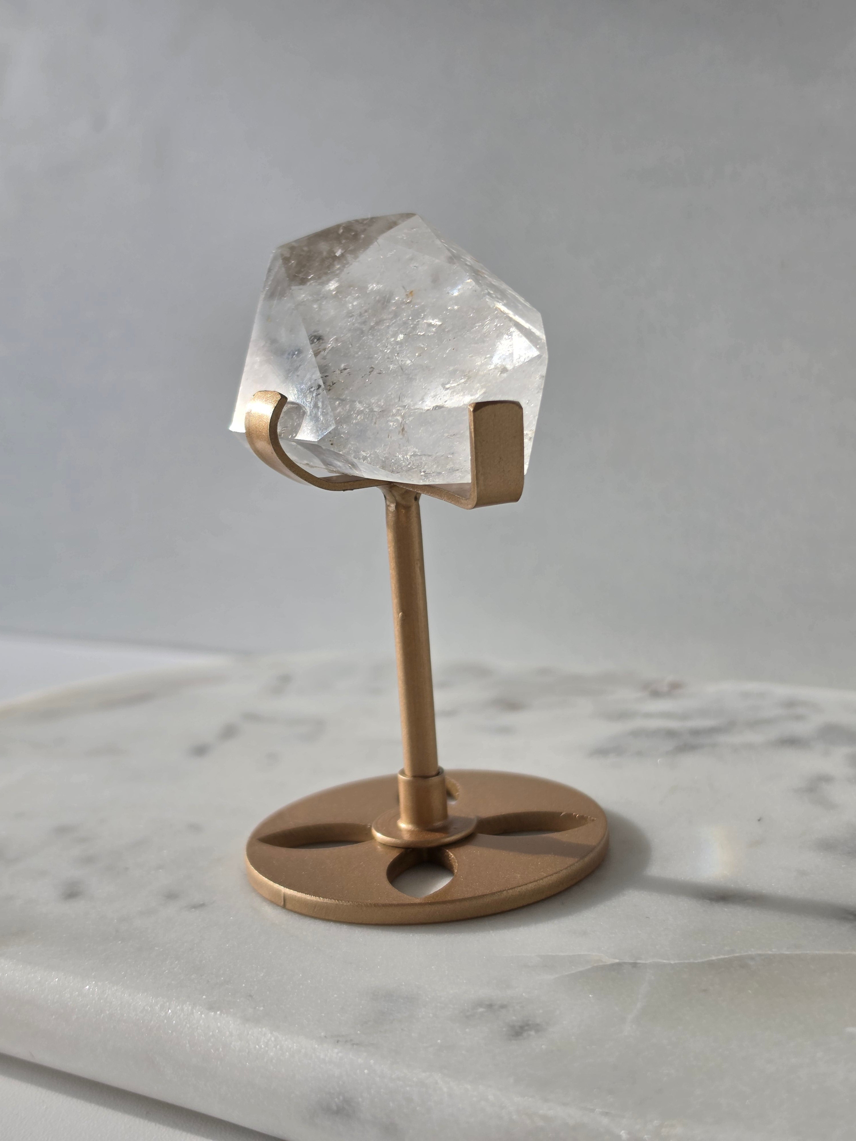 Clear Quartz freeform crystal with natural internal inclusions and luminous clarity, displayed on an elegant gold-finished stand.