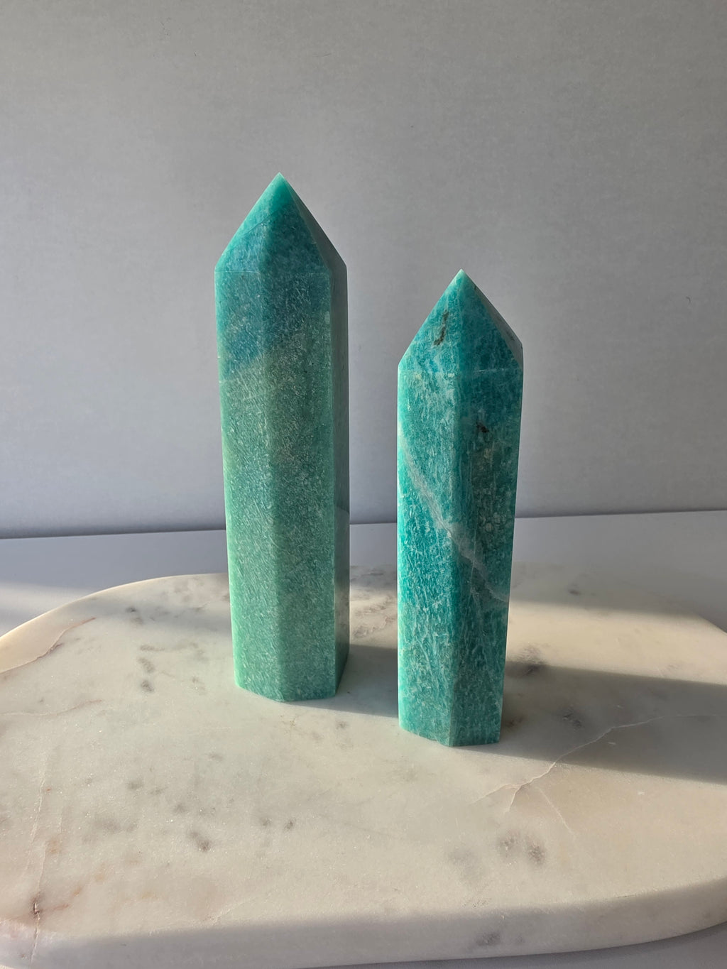 Natural Amazonite tower in soft mint and sea-green tones with subtle blue-green variations, polished geometric point and delicate natural inclusions, displayed as a luxury crystal statement piece.