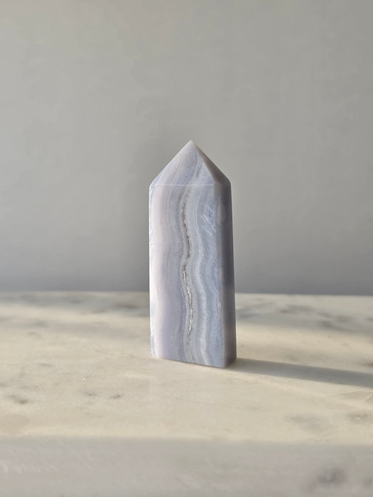 Natural Blue Lace Agate crystal point with soft blue and white banding, polished finish and unique natural formations