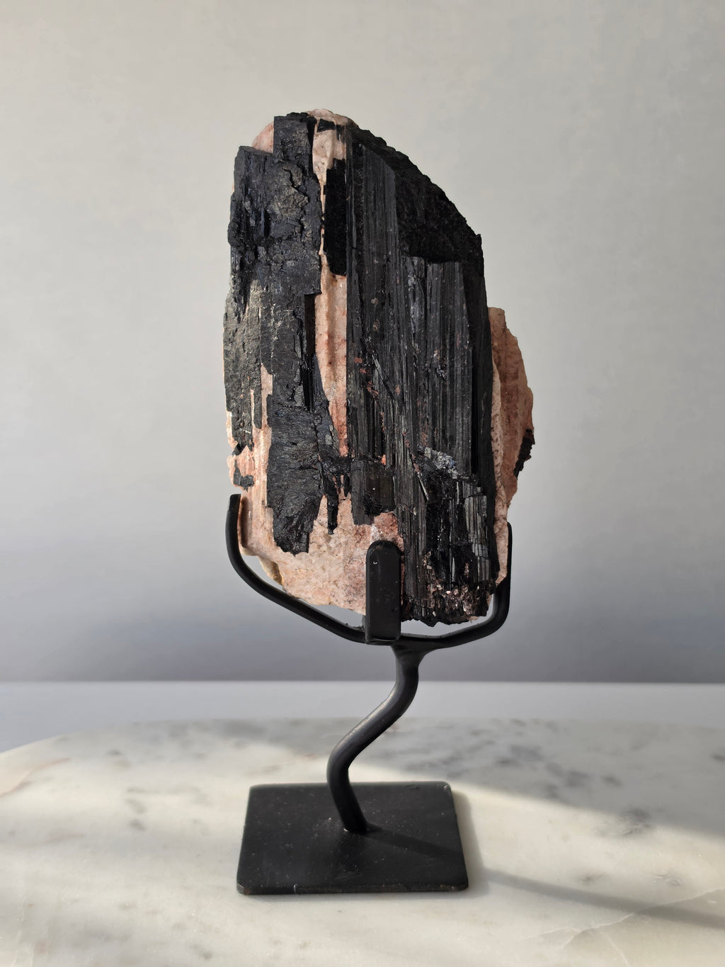 Black Tourmaline on Feldspar matrix from Brazil featuring naturally formed black crystals, contrasting pale matrix, black display stand, 910g, 19.5 × 6.5cm.