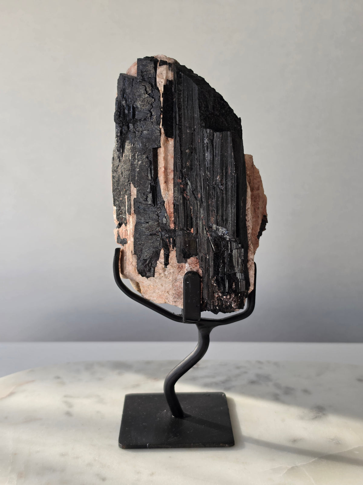 Black Tourmaline on Feldspar matrix from Brazil featuring naturally formed black crystals, contrasting pale matrix, black display stand, 910g, 19.5 × 6.5cm.