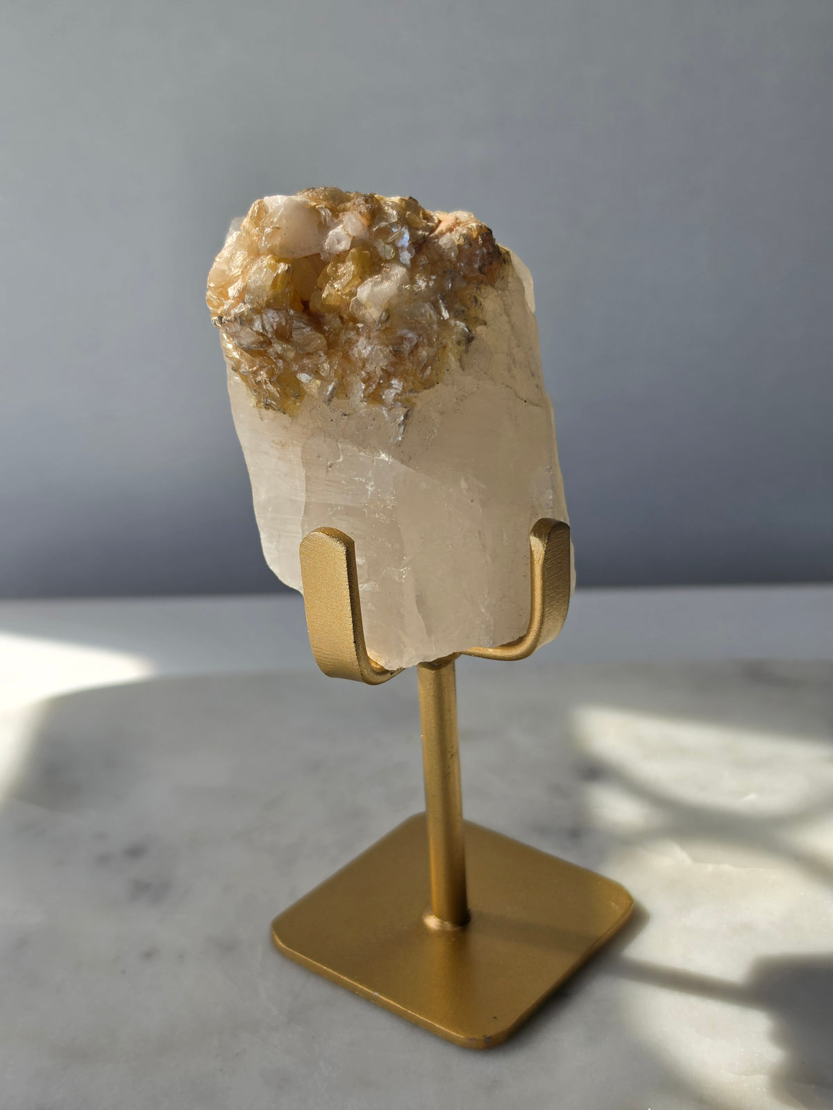 Brazilian Golden Mica on Matrix mineral specimen featuring shimmering golden mica crystals within a pale translucent matrix, displayed on a gold-toned stand.
