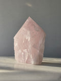 Natural Rose Quartz tower with soft blush-pink colouring, translucent areas and organic crystal formations, weighing 298g and measuring 9.5cm