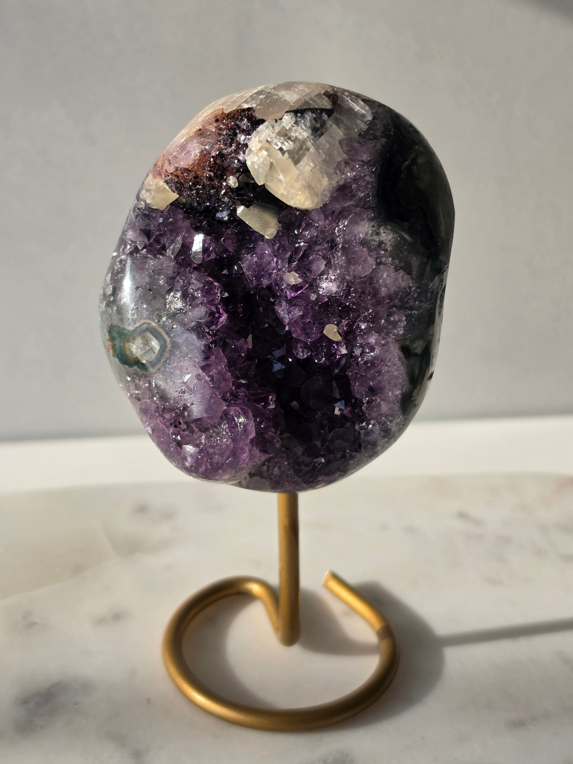 Natural Amethyst Stalactite with Calcite inclusions and blush red tones on a luxury gold display stand