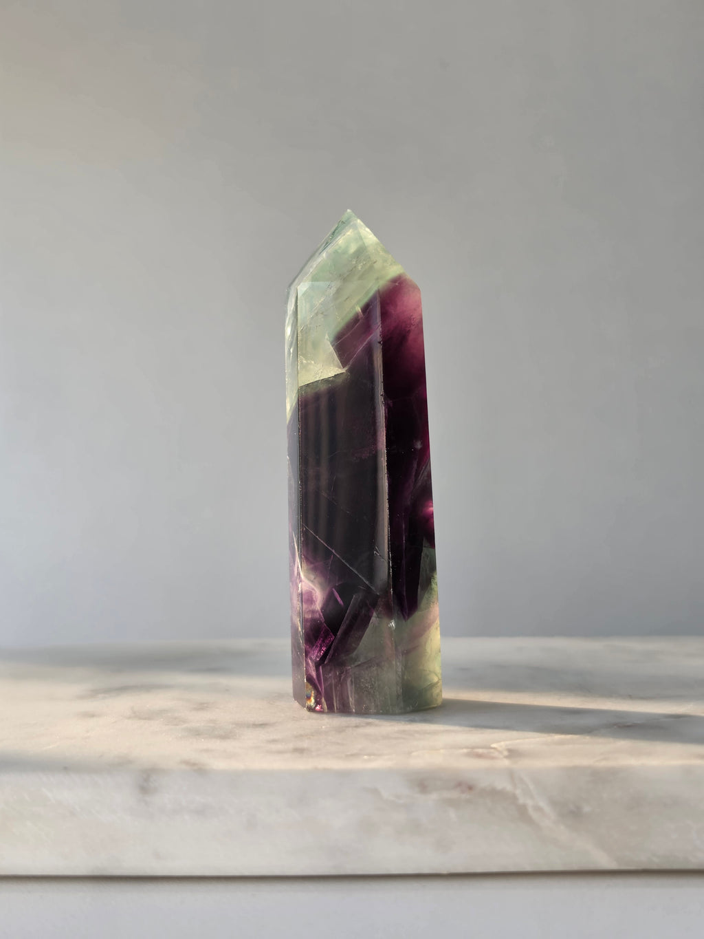 Natural Fluorite crystal point with deep purple and light green colour zoning, transparent polished finish and unique internal formations