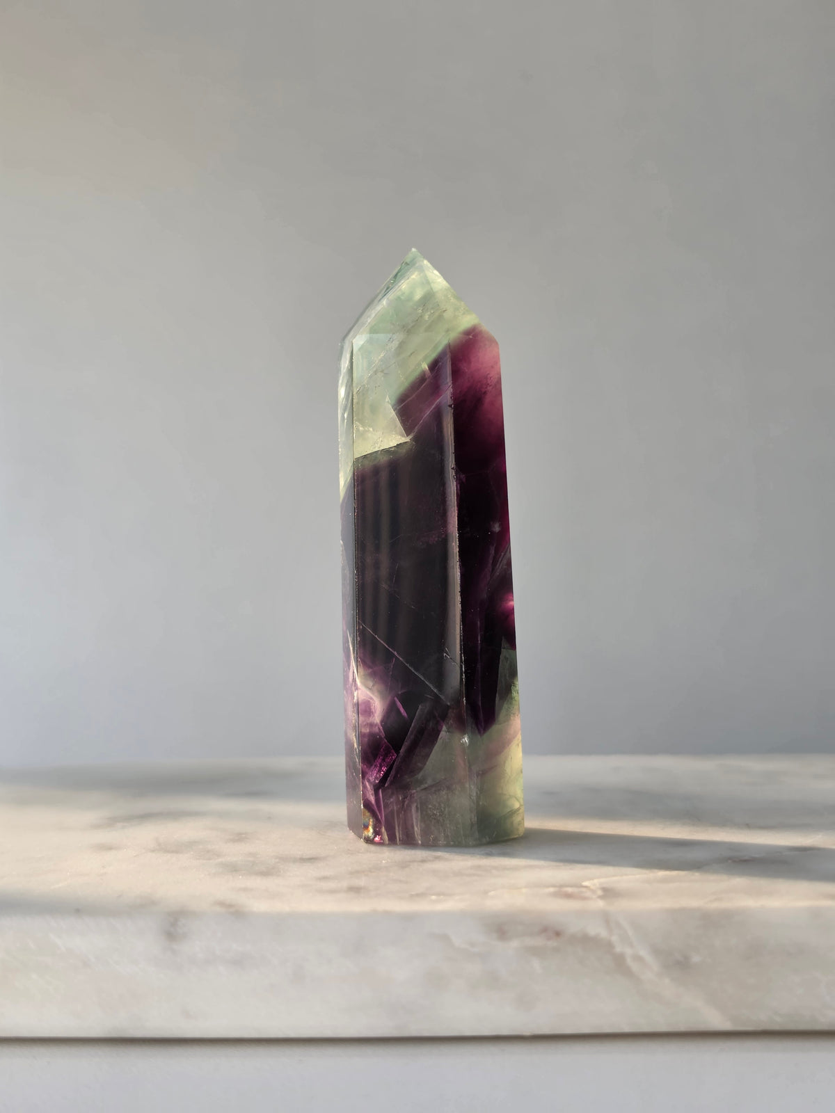 Natural Fluorite crystal point with deep purple and light green colour zoning, transparent polished finish and unique internal formations