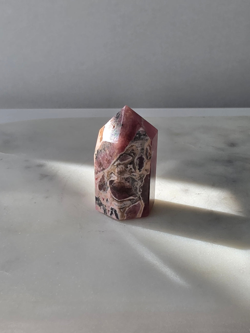 Polished Argentine Rhodochrosite crystal point with deep raspberry pink colour and intricate cream, blush and dark mineral banding, 37g, 4cm.