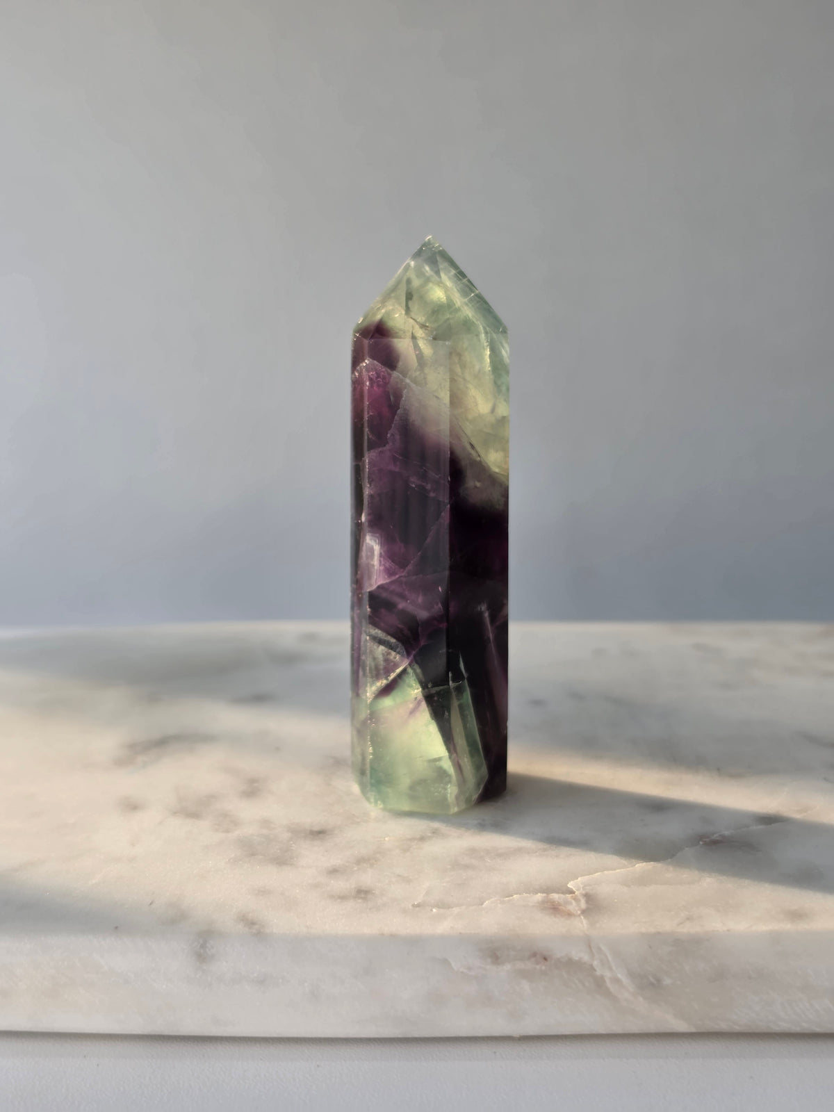 Natural Fluorite crystal point with deep purple and light green colour zoning, transparent polished finish and unique internal formations