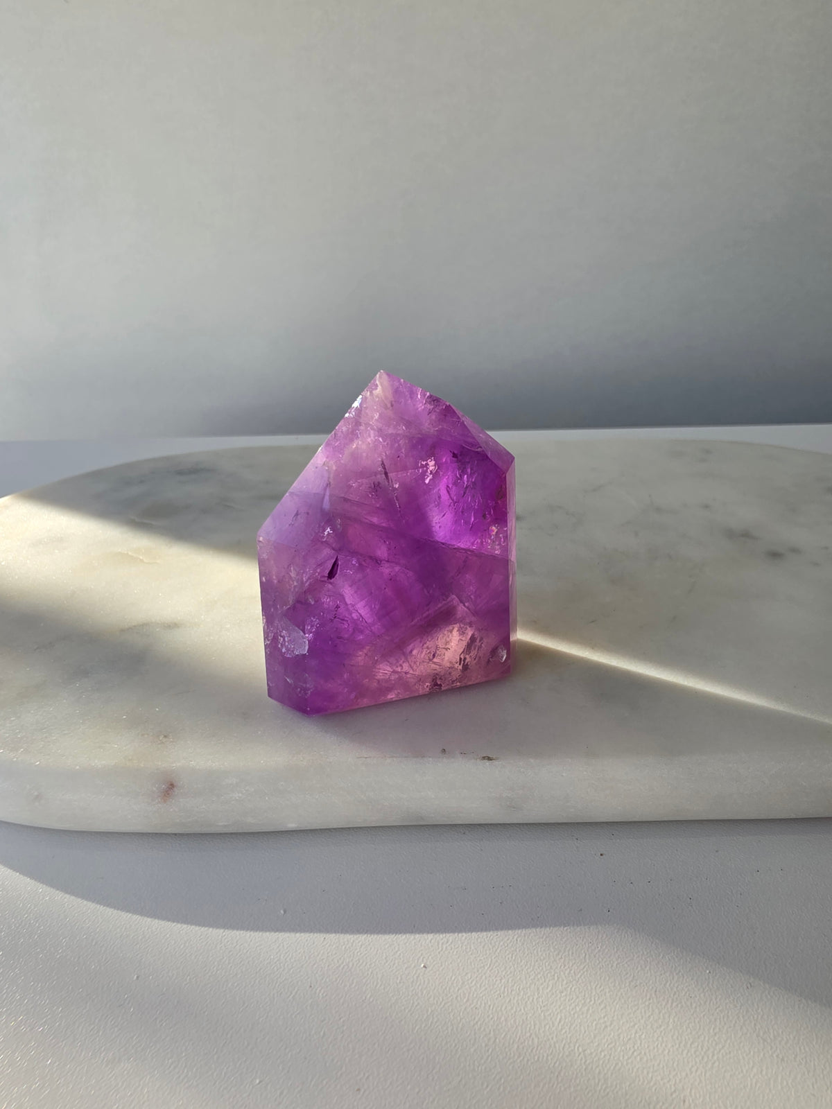 High clarity purple Amethyst tower from Brazil featuring rich violet and lavender hues, translucent crystal formations and polished reflective facets.