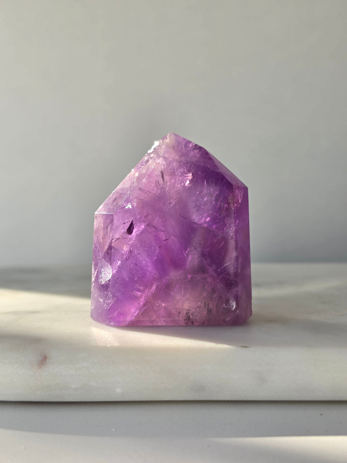 High clarity purple Amethyst tower from Brazil featuring rich violet and lavender hues, translucent crystal formations and polished reflective facets.
