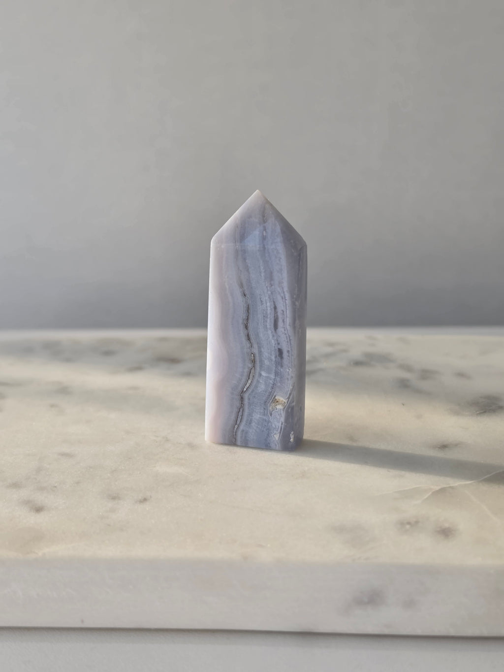 Natural Blue Lace Agate crystal point with soft blue and white banding, polished finish and unique natural formations