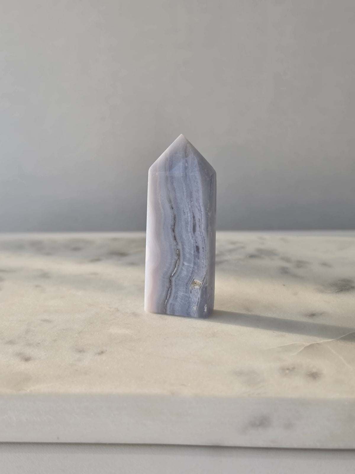 Natural Blue Lace Agate crystal point with soft blue and white banding, polished finish and unique natural formations